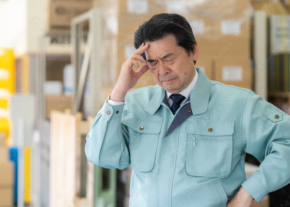 ハンガー輸送の現場課題に悩むアパレル物流担当者。掛け替え作業や人手不足による負担をイメージした写真。